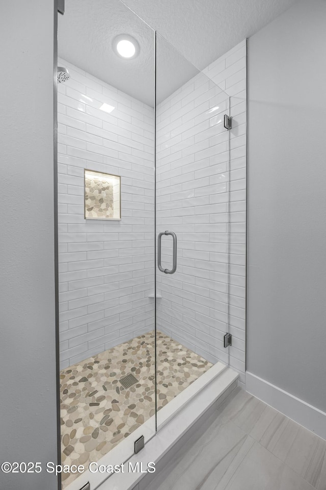 bathroom featuring a shower with shower door and a textured ceiling