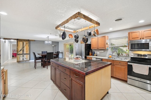 kitchen with a center island, appliances with stainless steel finishes, sink, and light tile patterned floors