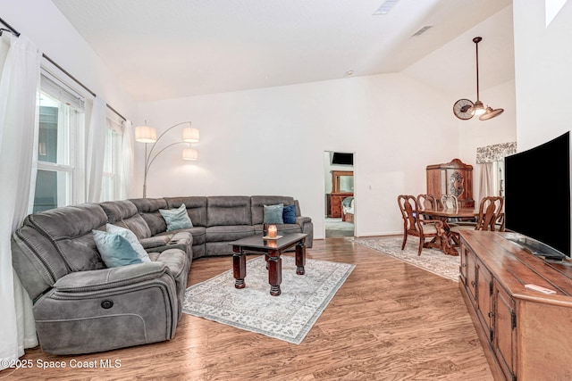 living room featuring hardwood / wood-style flooring, high vaulted ceiling, and a chandelier