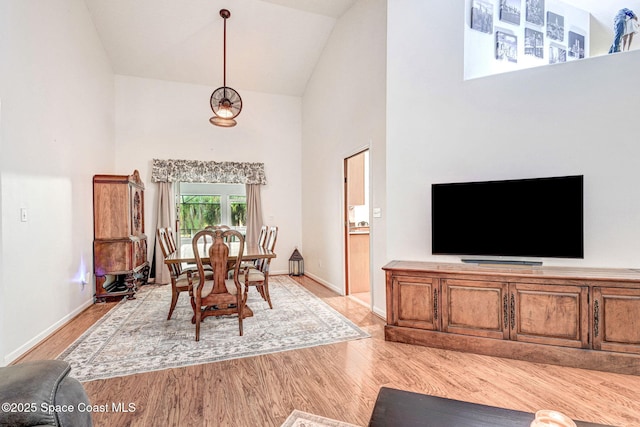 dining area with high vaulted ceiling and light hardwood / wood-style floors