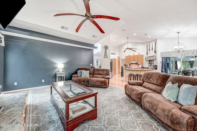 living room with ceiling fan with notable chandelier, high vaulted ceiling, and a textured ceiling