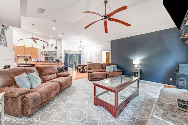 living room with ceiling fan with notable chandelier, light wood-type flooring, and high vaulted ceiling