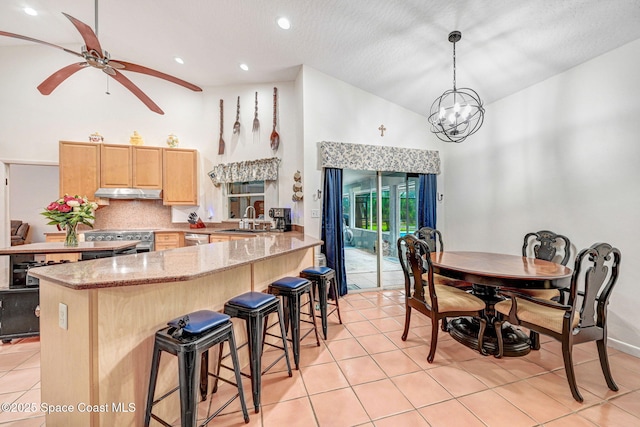 kitchen with stainless steel appliances, decorative light fixtures, light brown cabinets, sink, and kitchen peninsula