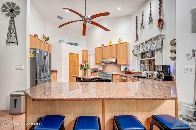 kitchen with a kitchen bar, sink, stainless steel appliances, kitchen peninsula, and decorative backsplash