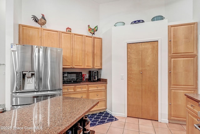 kitchen featuring light brown cabinetry, light tile patterned floors, light stone countertops, and stainless steel refrigerator with ice dispenser