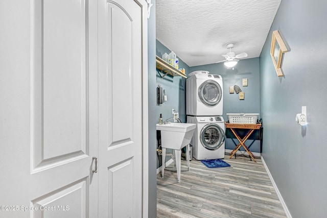 washroom featuring hardwood / wood-style floors, ceiling fan, a textured ceiling, and stacked washing maching and dryer