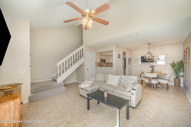 living room with ceiling fan with notable chandelier, light tile patterned floors, and lofted ceiling