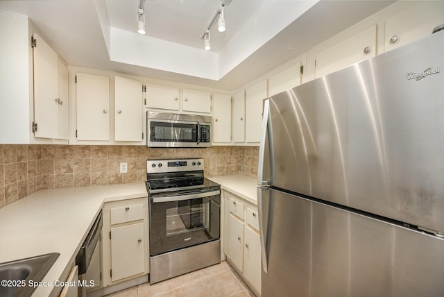 kitchen with light tile patterned flooring, sink, appliances with stainless steel finishes, a raised ceiling, and decorative backsplash