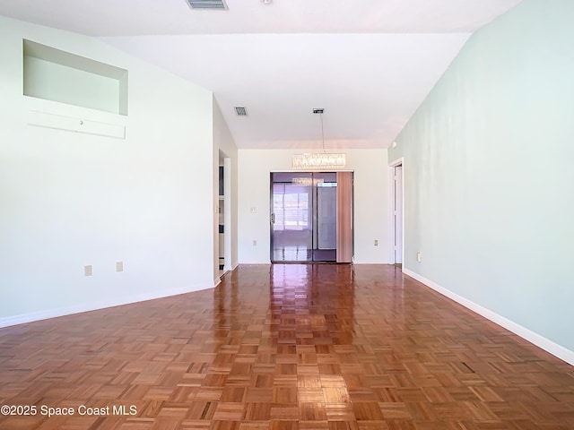 empty room with dark parquet flooring and a notable chandelier