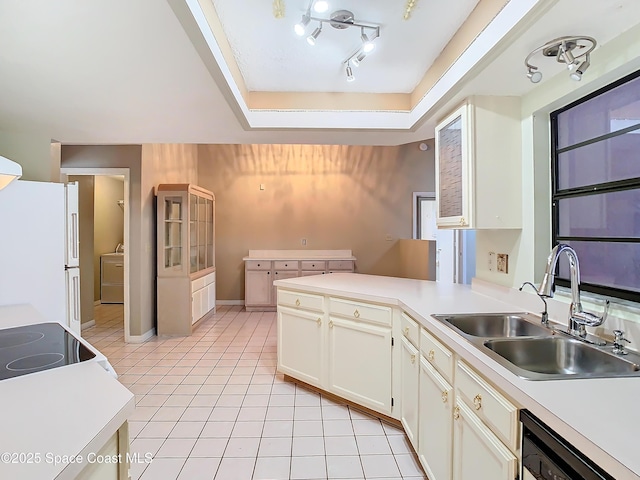 kitchen featuring sink, light tile patterned floors, a tray ceiling, white appliances, and washer / clothes dryer