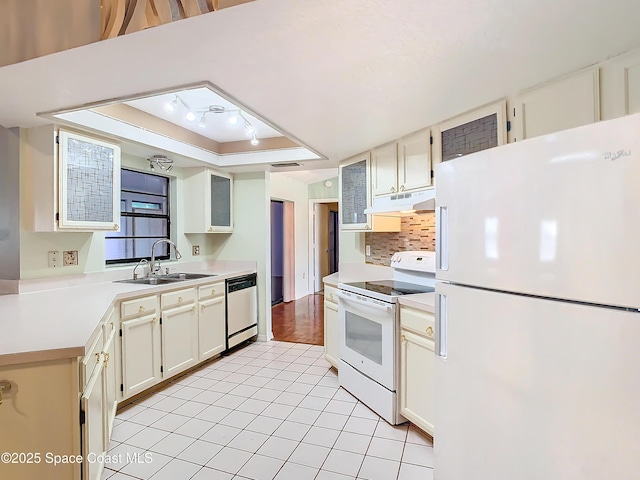 kitchen featuring light tile patterned flooring, sink, decorative backsplash, a raised ceiling, and white appliances