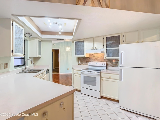 kitchen featuring sink, white appliances, light tile patterned floors, a tray ceiling, and decorative backsplash