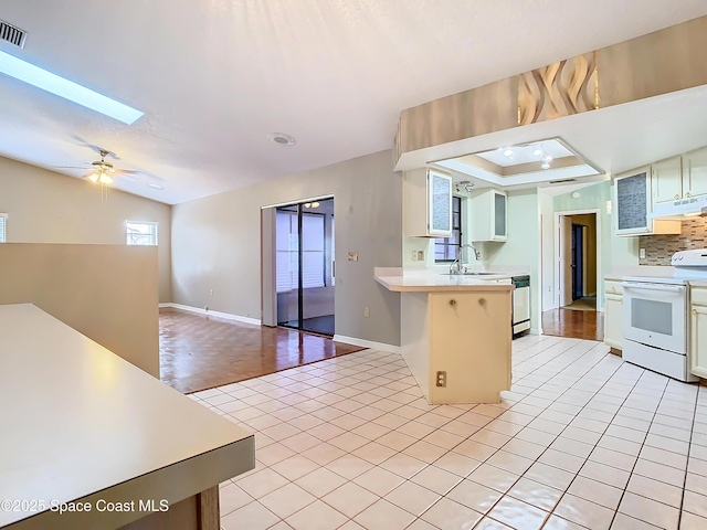 kitchen with sink, light tile patterned floors, a kitchen breakfast bar, a tray ceiling, and white electric stove