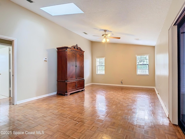 unfurnished room featuring ceiling fan, light parquet flooring, lofted ceiling with skylight, and a textured ceiling