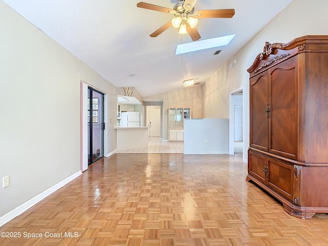 empty room featuring ceiling fan, vaulted ceiling with skylight, and light parquet floors