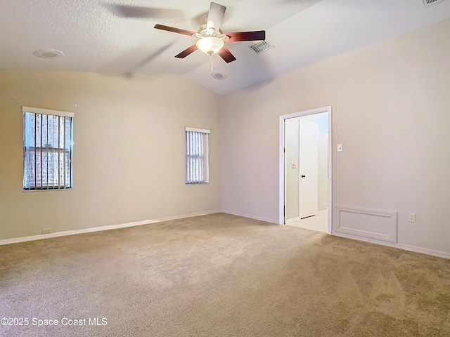 empty room featuring lofted ceiling, light colored carpet, a textured ceiling, and ceiling fan