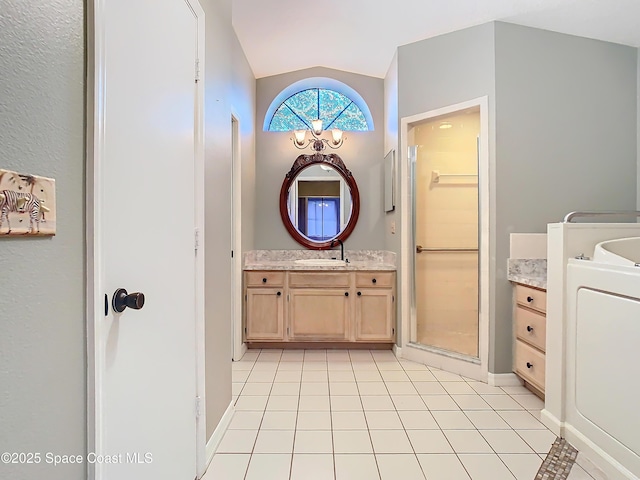 bathroom featuring lofted ceiling, vanity, washer / dryer, and tile patterned floors