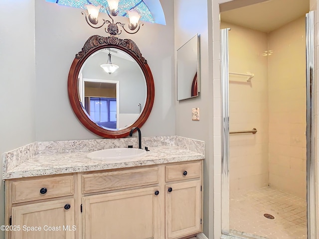 bathroom with an inviting chandelier, vanity, and tiled shower