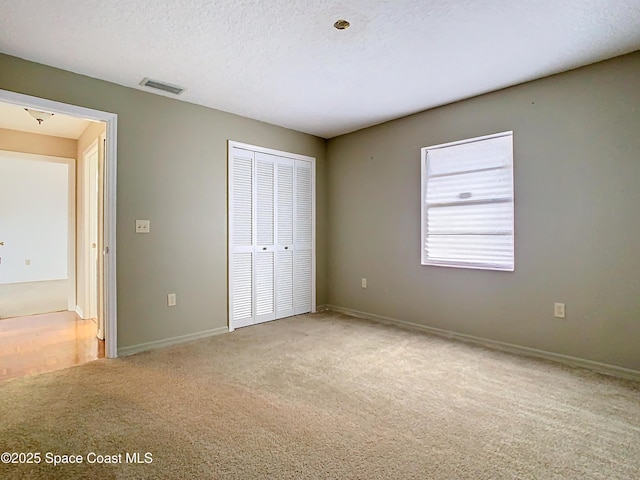 unfurnished bedroom with carpet floors, a closet, and a textured ceiling