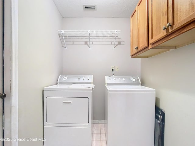 laundry room featuring separate washer and dryer, cabinets, and a textured ceiling