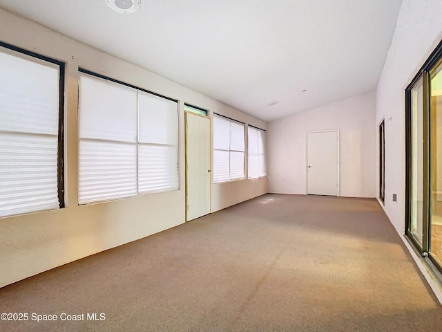 empty room with carpet floors and vaulted ceiling