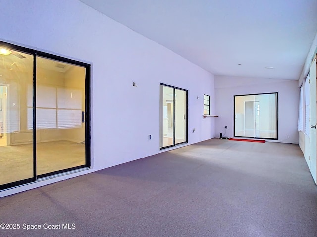 carpeted empty room with plenty of natural light and vaulted ceiling