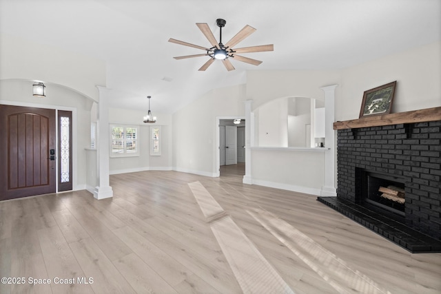 unfurnished living room featuring vaulted ceiling, a brick fireplace, ceiling fan, and light wood-type flooring