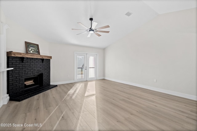 unfurnished living room featuring french doors, vaulted ceiling, light wood-type flooring, ceiling fan, and a fireplace