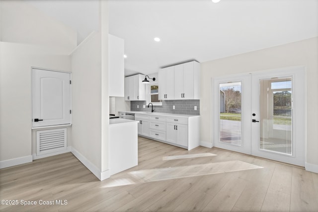 kitchen with french doors, sink, white cabinetry, tasteful backsplash, and light wood-type flooring