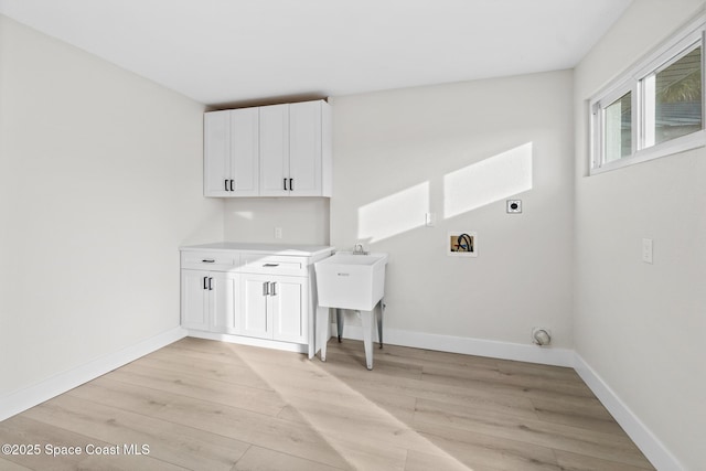 clothes washing area featuring cabinets, hookup for a washing machine, light hardwood / wood-style floors, and hookup for an electric dryer