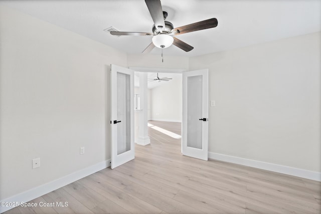 empty room with french doors, ceiling fan, and light wood-type flooring