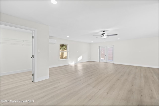 unfurnished room featuring light hardwood / wood-style floors, an AC wall unit, and ceiling fan