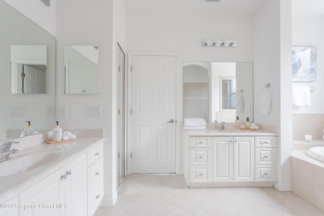 bathroom featuring tile patterned flooring, vanity, and a relaxing tiled tub