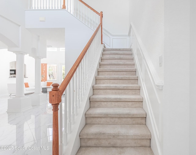 staircase with decorative columns and a high ceiling