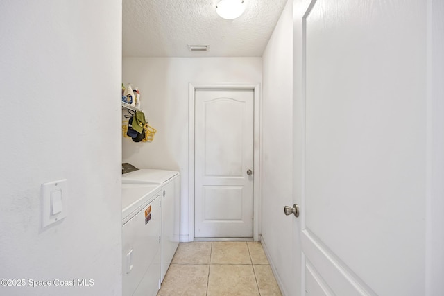 laundry room with light tile patterned floors, washing machine and clothes dryer, and a textured ceiling