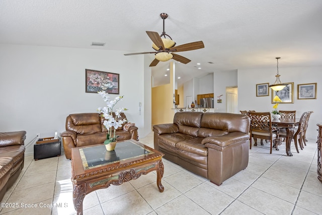 tiled living room featuring ceiling fan, lofted ceiling, and a textured ceiling