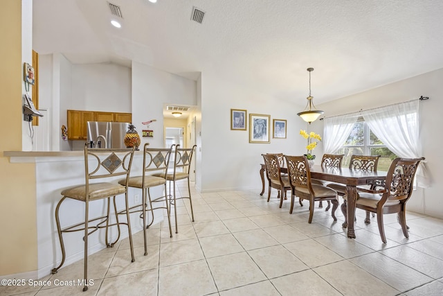 tiled dining room with lofted ceiling and a textured ceiling