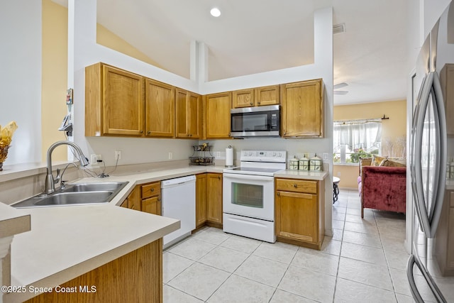 kitchen featuring stainless steel appliances, kitchen peninsula, sink, and light tile patterned floors