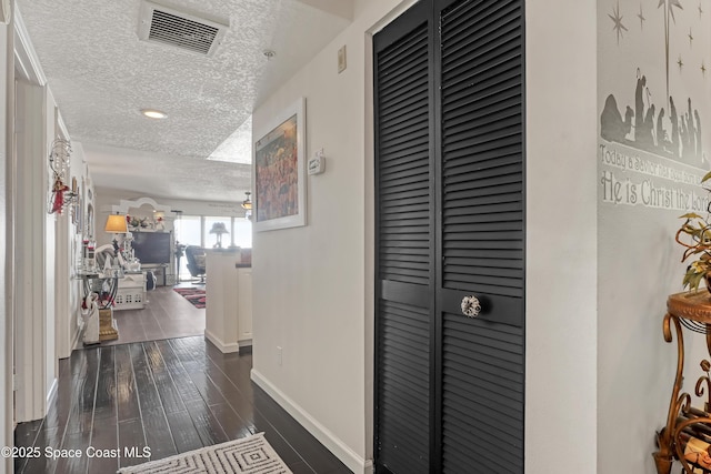 hall featuring dark wood-type flooring and a textured ceiling