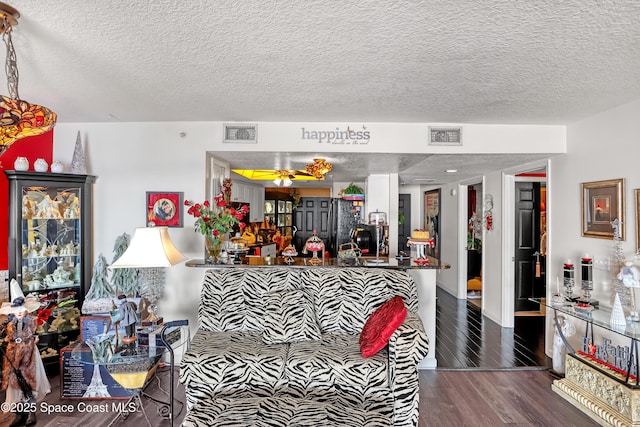 kitchen featuring dark wood-type flooring, kitchen peninsula, a textured ceiling, and black fridge