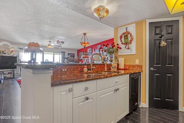 kitchen featuring sink, dishwasher, white cabinetry, a textured ceiling, and kitchen peninsula