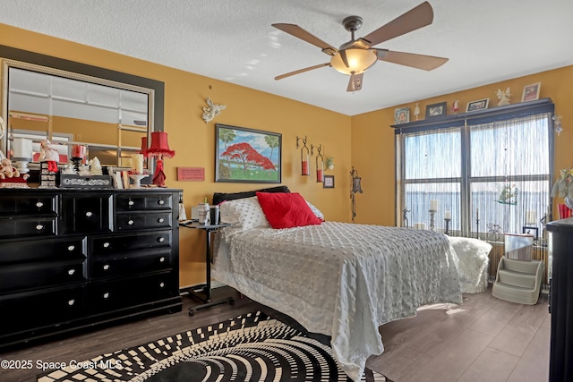 bedroom with hardwood / wood-style flooring, ceiling fan, and a textured ceiling