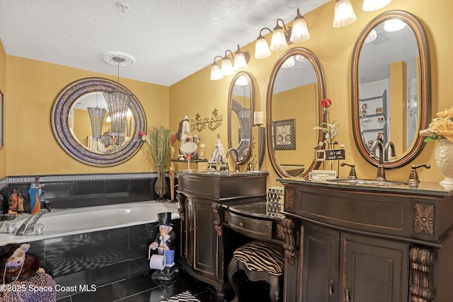 bathroom featuring vanity, a relaxing tiled tub, and a textured ceiling