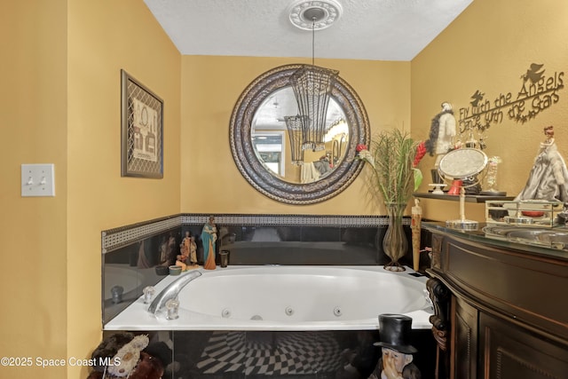 bathroom with a relaxing tiled tub, vanity, and a textured ceiling