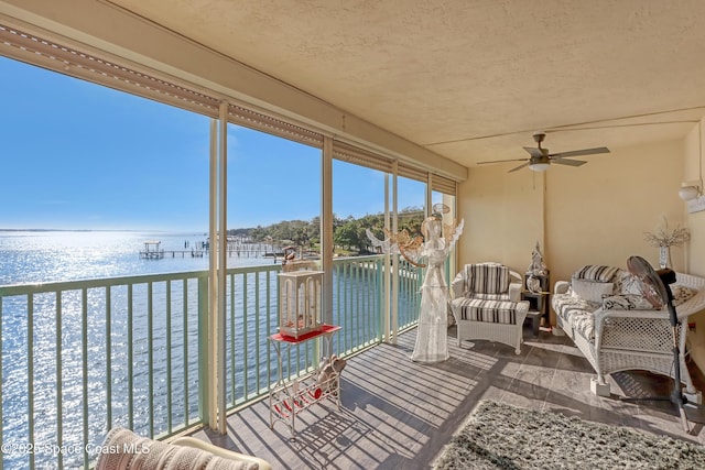 sunroom / solarium featuring a water view and ceiling fan