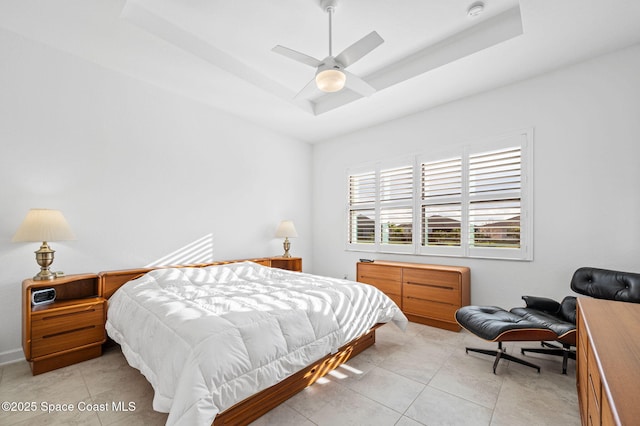 tiled bedroom featuring ceiling fan and a tray ceiling