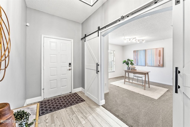 entrance foyer with a barn door, light hardwood / wood-style floors, and a textured ceiling