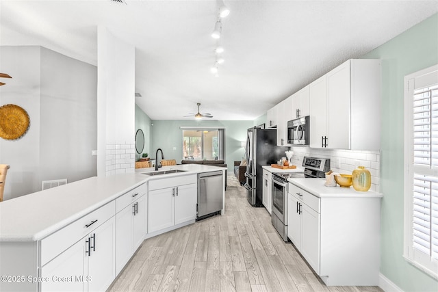 kitchen featuring sink, white cabinetry, stainless steel appliances, tasteful backsplash, and kitchen peninsula