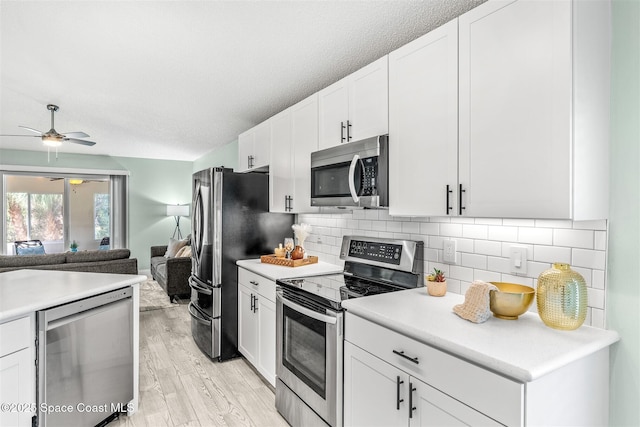 kitchen featuring white cabinetry, stainless steel appliances, tasteful backsplash, and light wood-type flooring