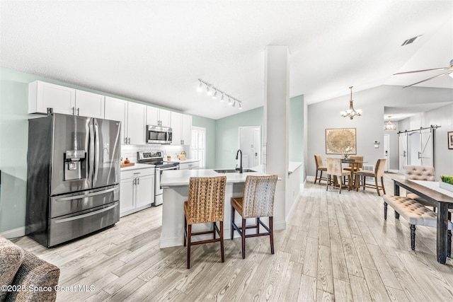 kitchen with stainless steel appliances, an island with sink, and white cabinets